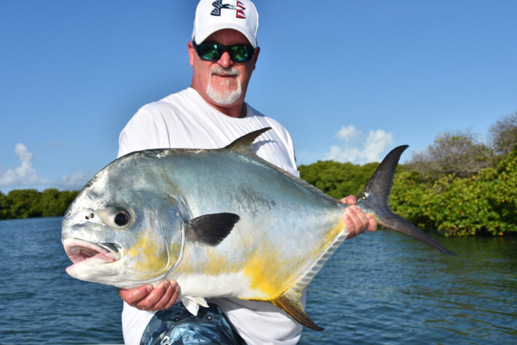 an angler holds up a monster permit he caught on the flats off of key west