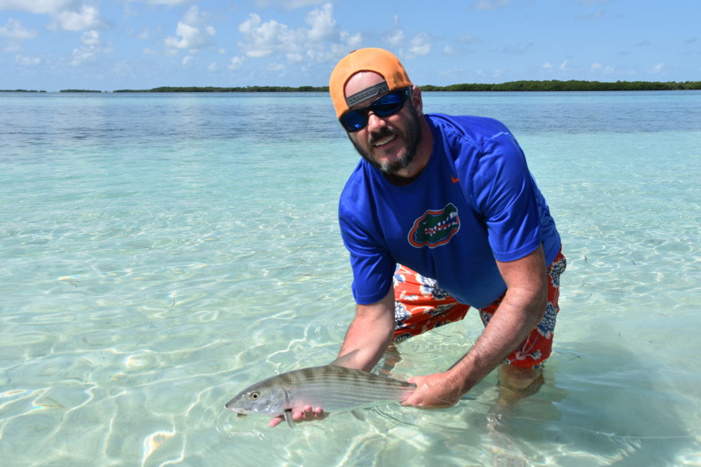an angler poses with a bonefish he caught while sight fishing in the shallow flats of the Florida keys