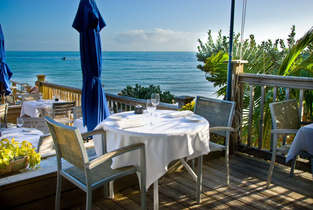 the view of the outside dining area at Louies backyard with white linen table cloth and a view right on the the Atlantic ocean