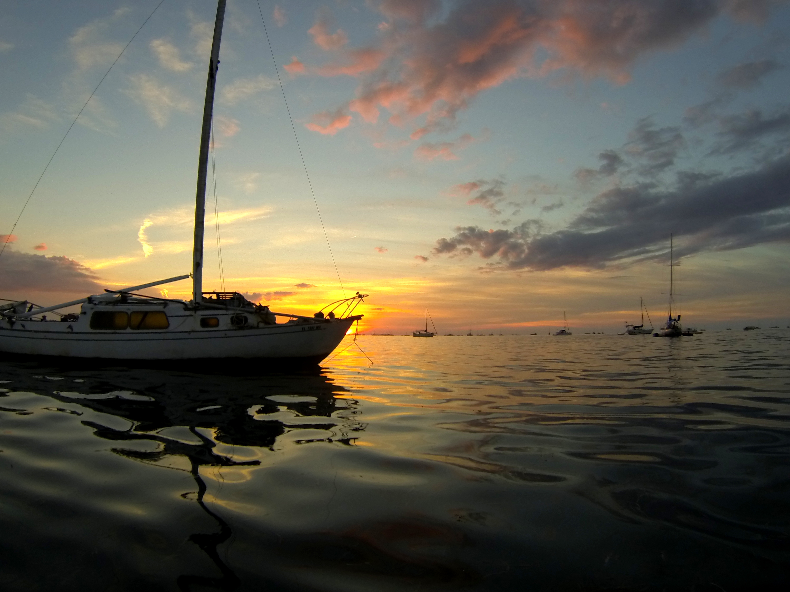 A sailboat blocks the last seconds of the setting sun on a glass calm afternoon in key west.