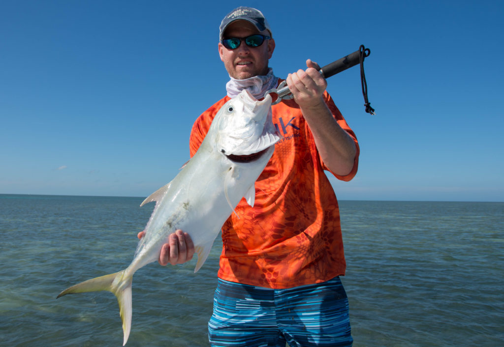An angler is holding up a ten pound jack crevalle using a boga grip on a sunny day in Key West.