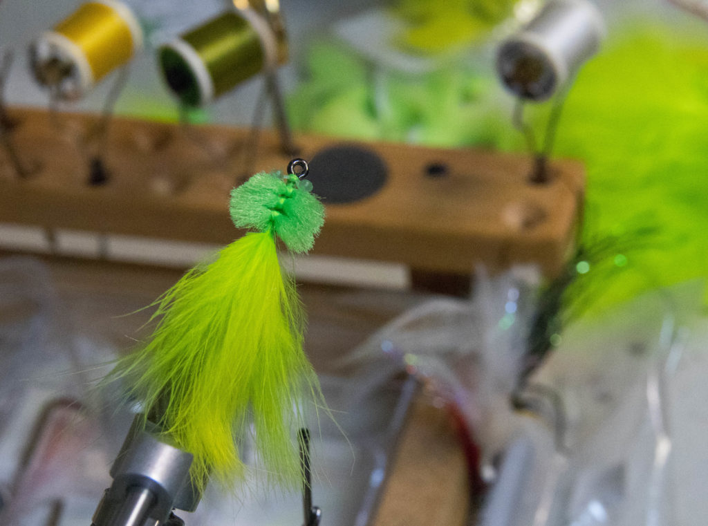 a chartreuse tarpon toad fly sits on the fly tying table