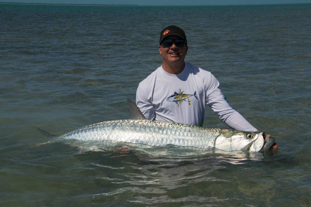 An angler is in the water holding a huge tarpon on the flats off of Key West, Florida.